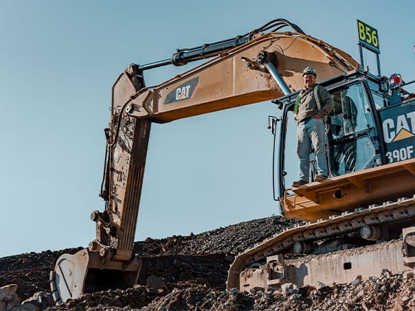 A TNDC equipment operator poses on a TNDC excavator