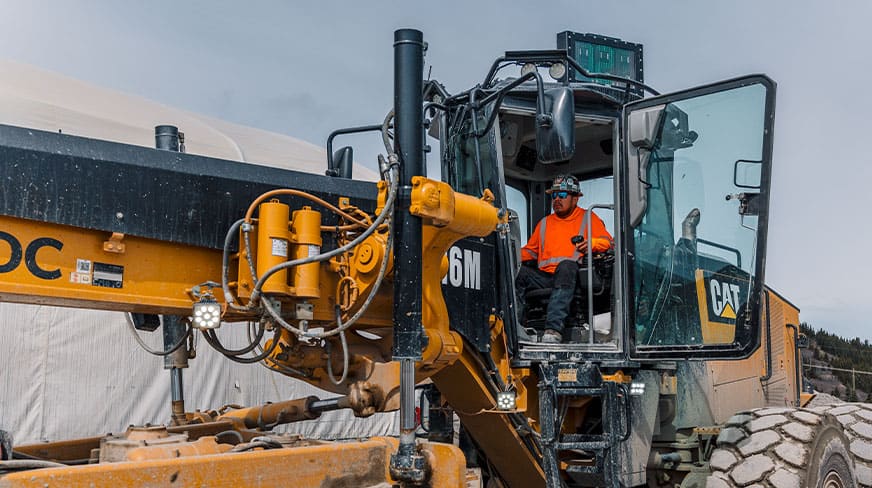 A TNDC operator poses in his equipment at our Red Chris project site